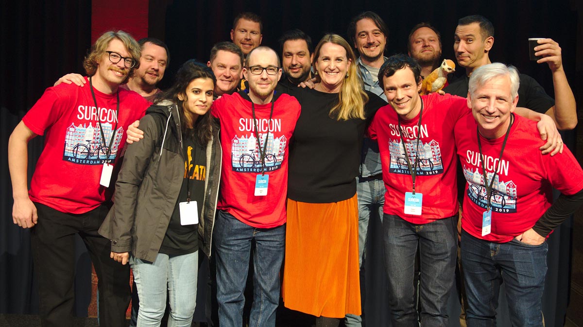 A picture with part of the Suricata mob posing during SuriCon Amsterdam. From left to right, on stagemany of them wearing SuriCon or Suricata t-shirts.